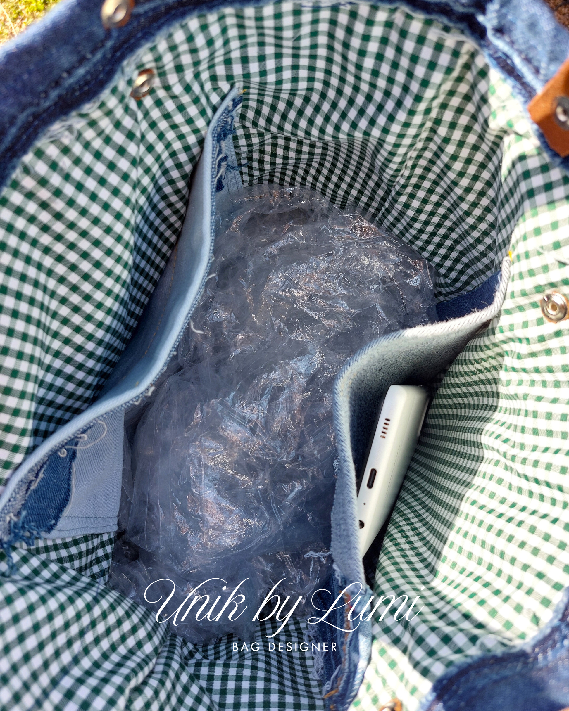 Close-up of a blue denim bag with green checkered lining